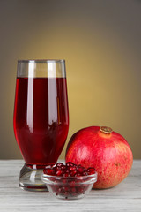 Glass of fresh garnet juice on table on gray background
