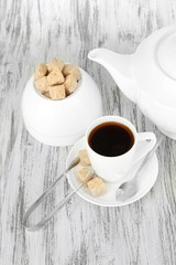 Cup of coffee, teapot and sugar-bowl on color wooden background