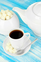 Cup of coffee, teapot and sugar-bowl on color wooden background