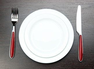 Knife, color plate and fork, on wooden background