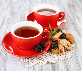 Cups of tea with cookies and blackberry on table close-up