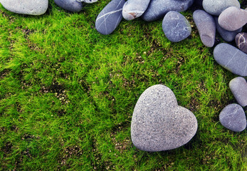 Grey stone in shape of heart, on grass background