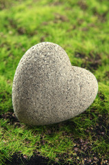 Grey stone in shape of heart, on grass background
