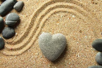 Fototapeta na wymiar Szary Zen kamień w kształcie serca, na tle piasku