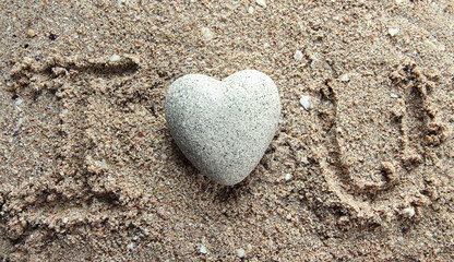 Grey stone in shape of heart, on sand background