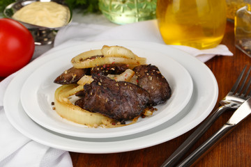 Fried chicken livers on plate on wooden table close-up