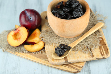 Fresh and dried plums in wooden bowl
