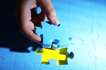 Hand holding puzzle piece, close up