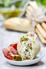 Italian cuisine: stuffed pasta shells and stack of breadsticks.