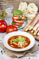 Italian cuisine: tomato soup, breadsticks with ham, caprese sala