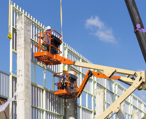 Worker to installation metal sheet on steel structure or frame for wall of facetory, warehouse or industrial building by boom lift or cherry picker and mobile crane for construction at height level. © DifferR