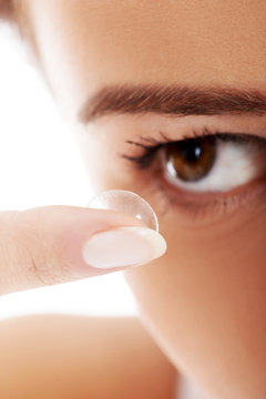 Close up on woman putting lens into eye.