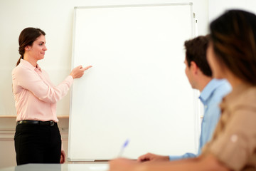 Pretty young businesswoman pointing at whiteboard