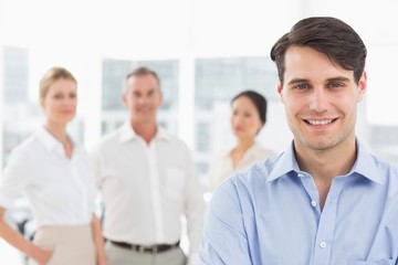 Fototapeta premium Smiling businessman standing with team behind him