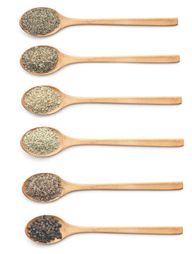 Various kind of spices on wooden spoon against white background