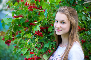 Teen girl near the red viburnum