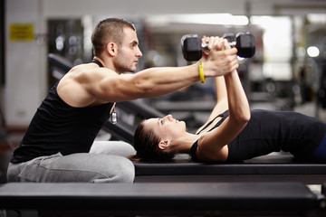 Fototapeta Personal trainer helping woman at gym obraz