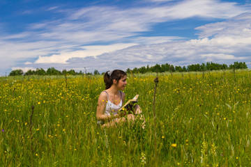Young woman reading book on a meadow