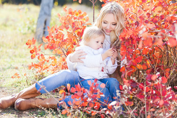 Young mother playing with her daughter in autumn park