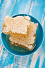 Honeycombs in a saucer, blue wooden background, above view