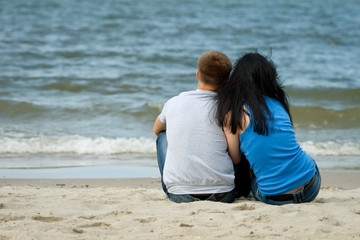 Fototapeta premium loving young couple is sitting near the sea