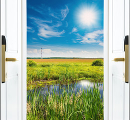 open door with a view of green meadow 