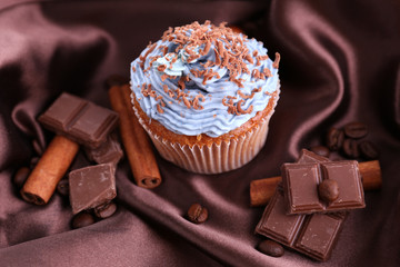 Tasty cupcake with butter cream, on color fabric background