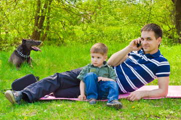 Man  with son and dog outdoors talking on the phone