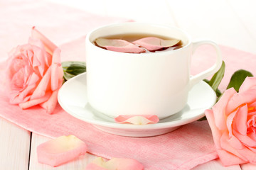 cup of tea with roses on white wooden table