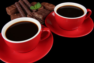 Red cups of strong coffee and chocolate bars close up