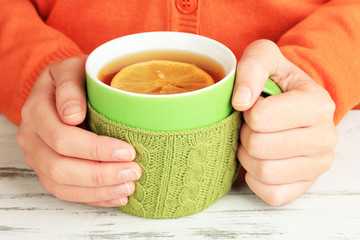 Cups with knitted things on it on wooden table close up