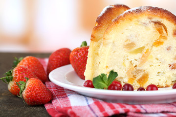 Slice of tasty homemade cake with berries, on wooden table