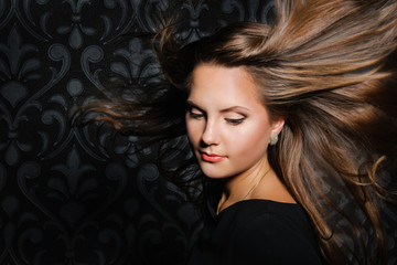 Beautiful Young Woman with long blowing hair, dark background