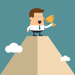 Young businessman lifts trophy atop high mountain peak.