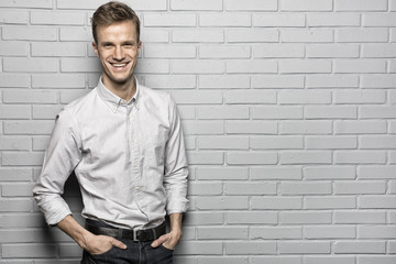 Handsome man standing on Grey wall background, looking camera