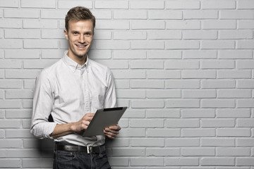 Handsome man standing on Gray wall background,Whith Tablet Pc