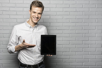 Handsome man standing on Grey wall background,Whith Tablet Pc