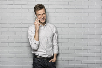 Handsome man standing on Grey wall background, on phone