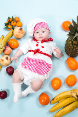 Baby cook girl wearing chef hat with fresh fruits.