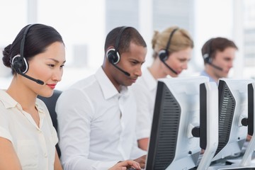 Colleagues with headsets using computers at office
