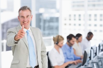 Businessman gesturing thumbs up with executives using computers