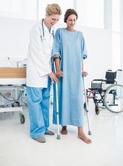 Doctor helping patient in crutches at the hospital