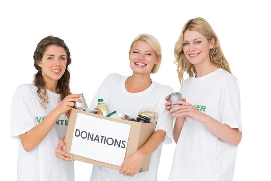 Portrait of three smiling young women with donation box