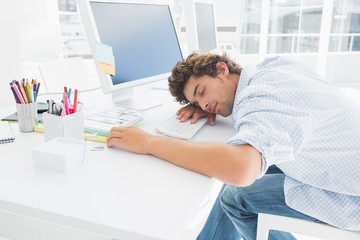 Casual businessman with head over keyboard in the office