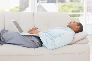 Businessman asleep on the couch with laptop