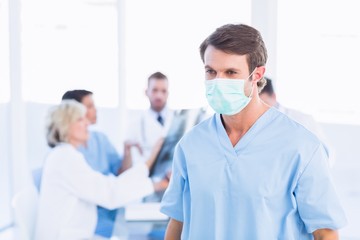 Fototapeta premium Male surgeon wearing mask with colleagues in meeting