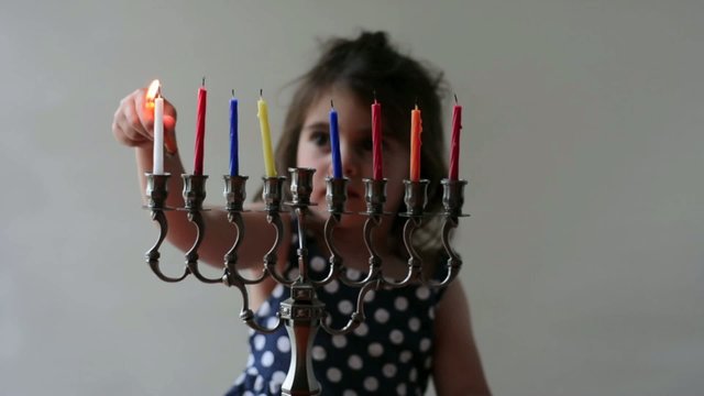 Jewish girl lit Hanukkah menorah during Hanukkah.