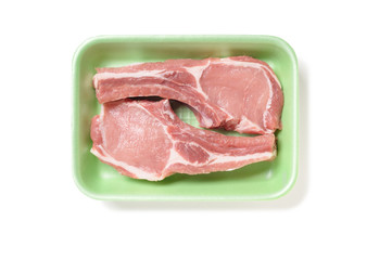 Two pork ribs in a green foam tray, isolated on white background