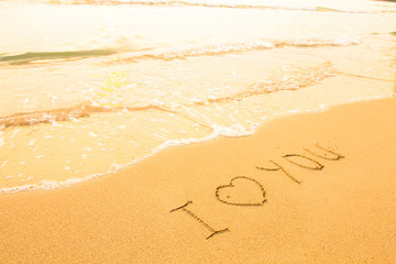 Fototapeta na wymiar I love you - inscription on the beach sand, soft surf wave.
