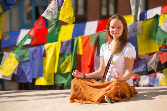 Girl sitting on Buddhist stupa, prayer flags